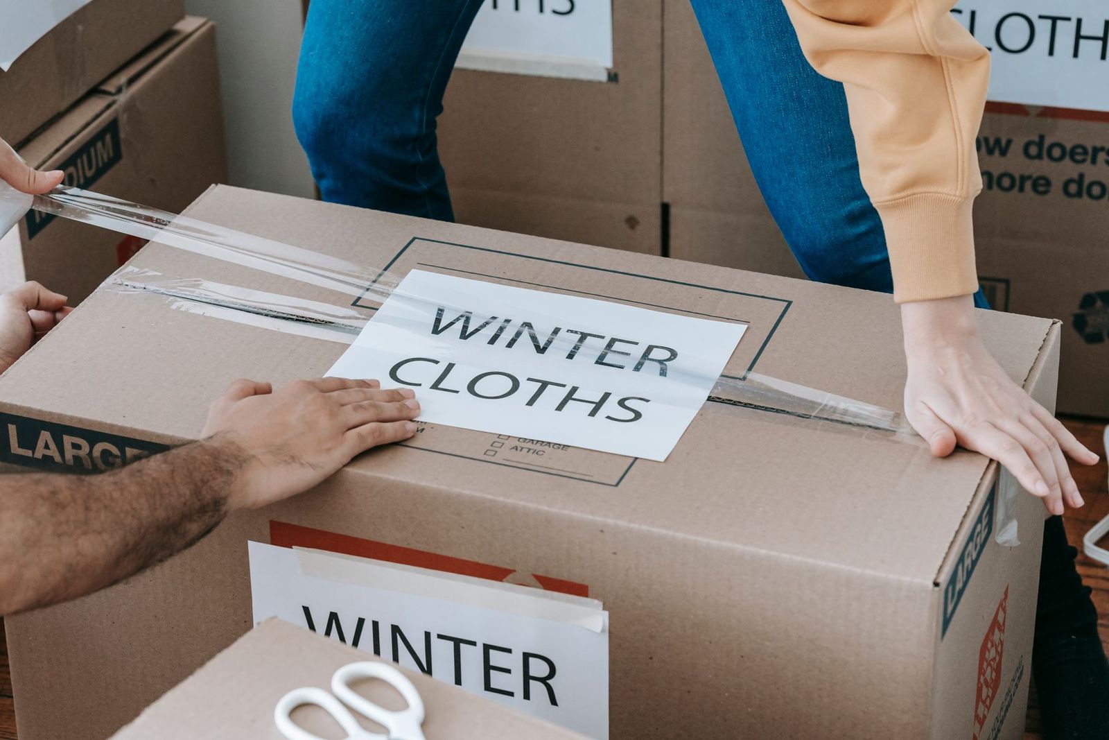 Hände packen einen beschrifteten Umzugskarton